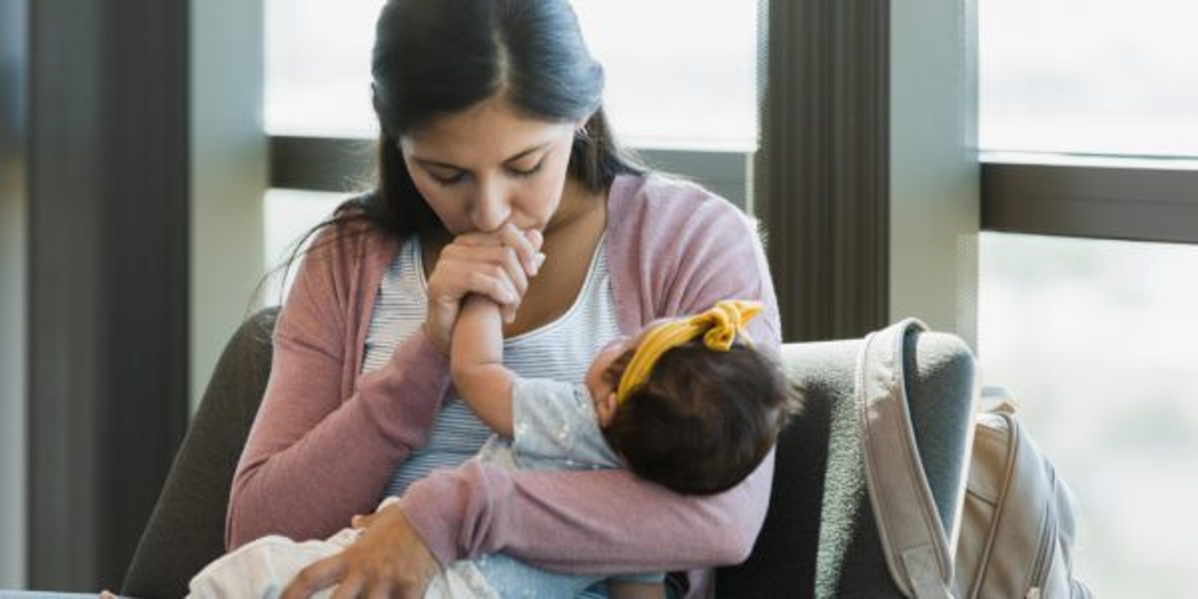 In doctor's waiting room, mother kisses baby's hand